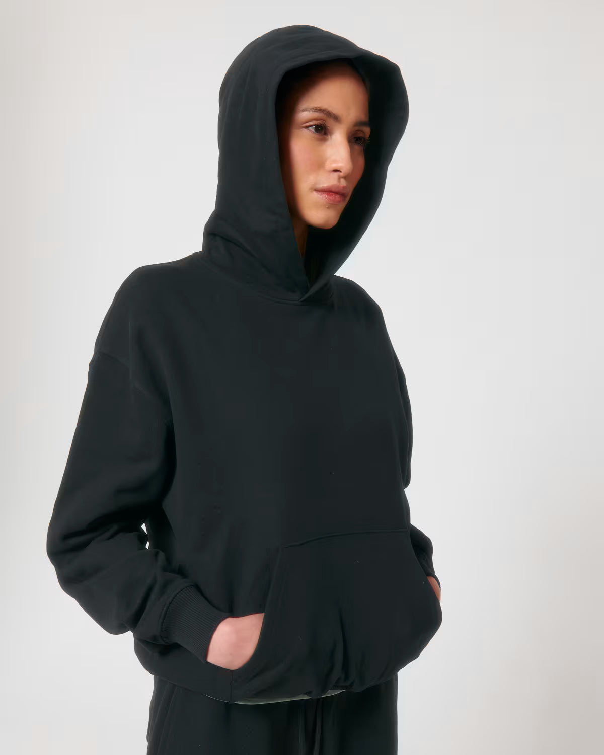 Front view of a female model wearing a black cotton hoodie in studio