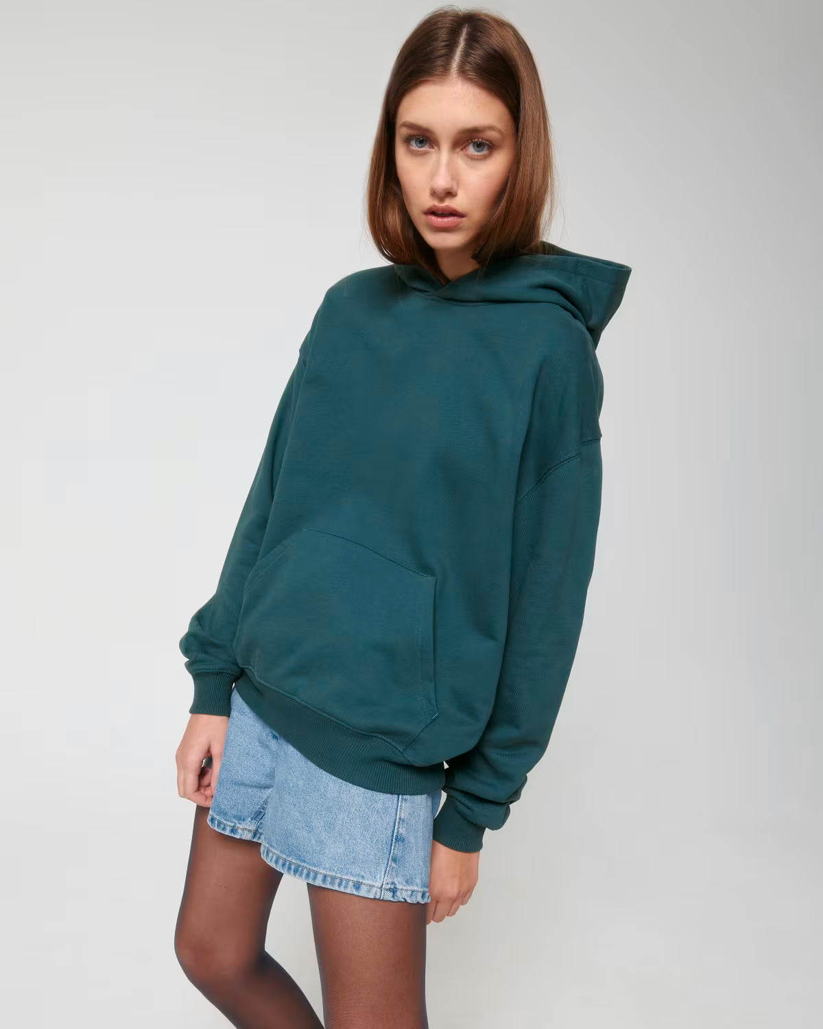 Front view of a female model wearing a teal cotton hoodie in studio