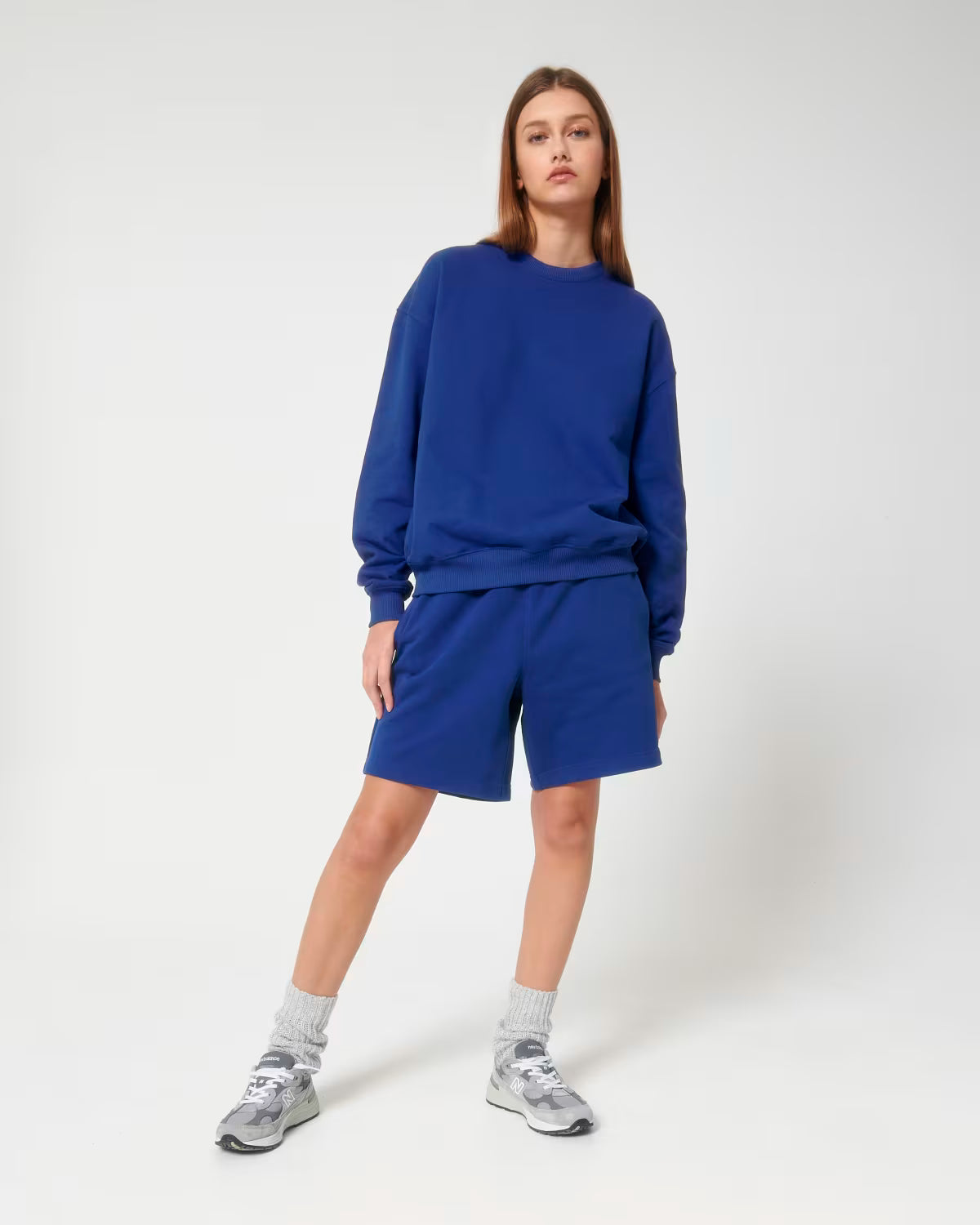 Full body view of a female model wearing a royal blue cotton hoodie in studio