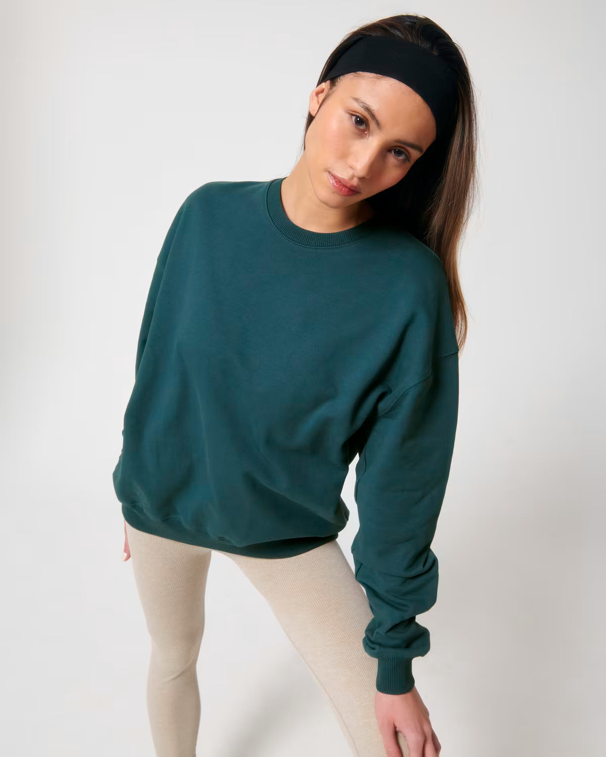 Front view of a female model wearing a teal cotton hoodie in studio