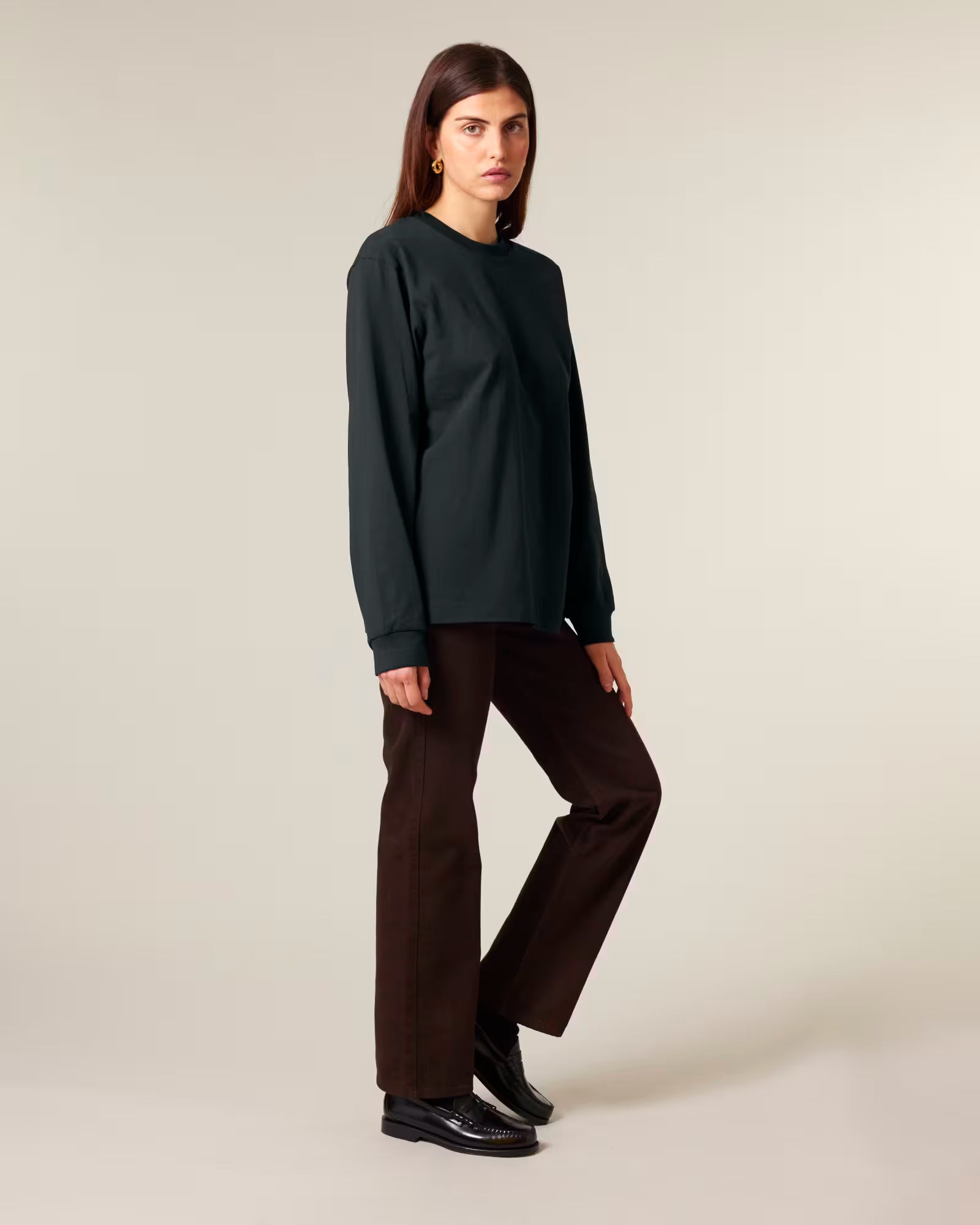 Full body view of a female model wearing a black cotton long sleeve t-shirt in studio