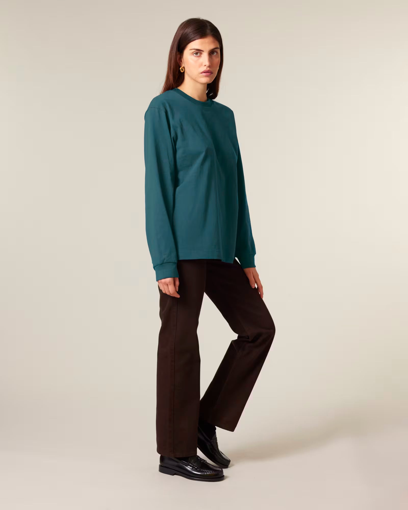 Full body view of a female model wearing a teal green cotton long sleeve t-shirt in studio