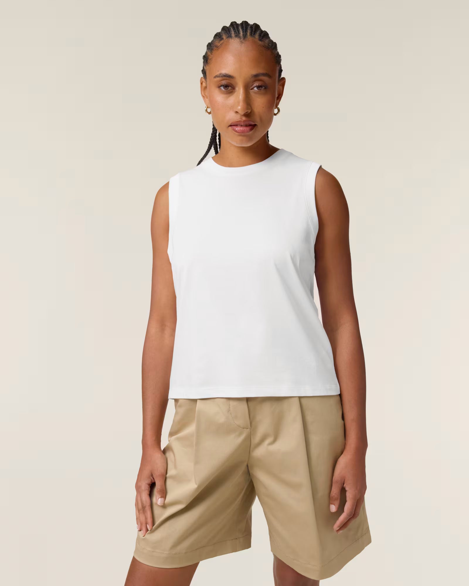 Front view of a female model wearing a white cotton sleeveless top in studio