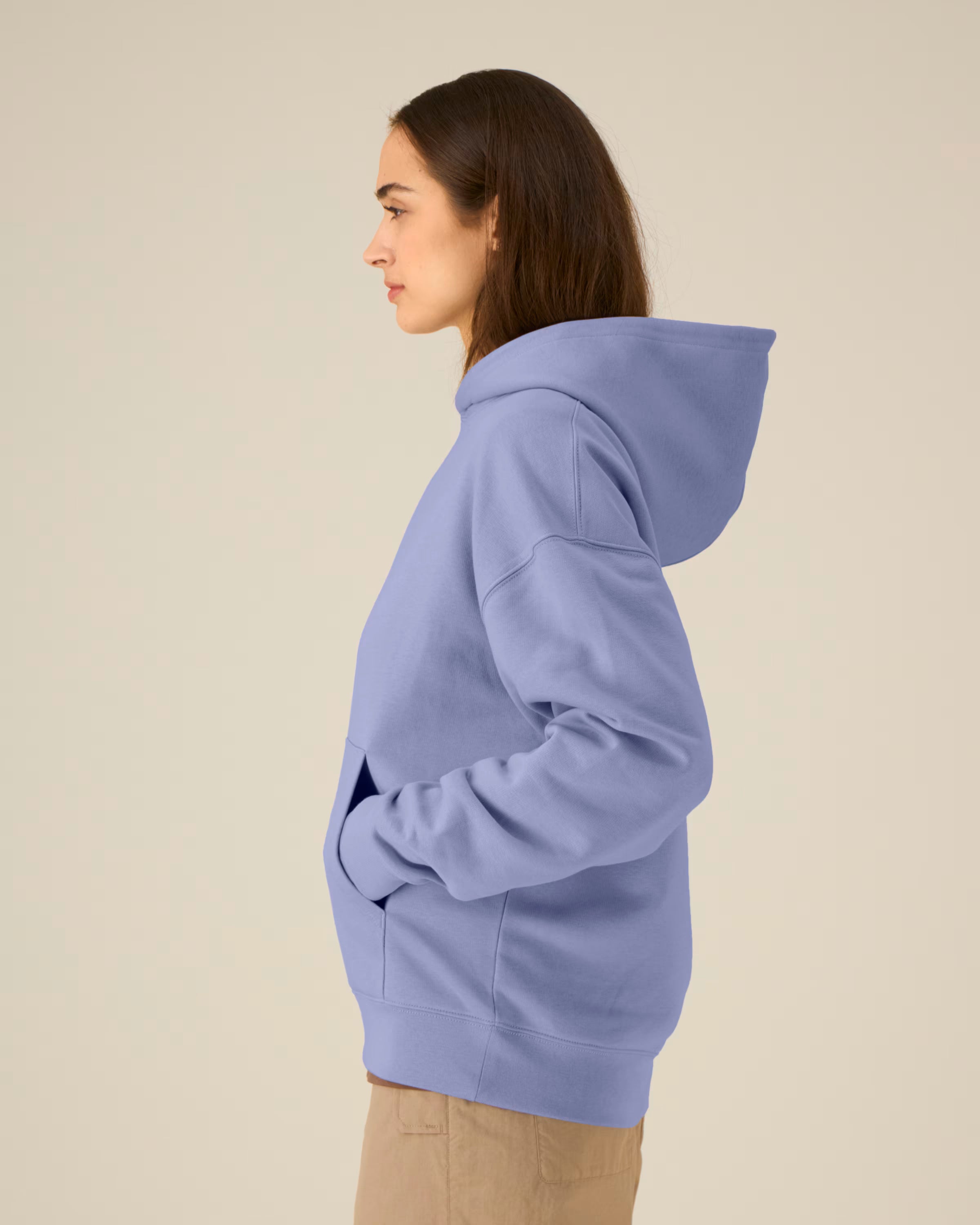 Person wearing a light blue unisex cotton hoodie on a beige background