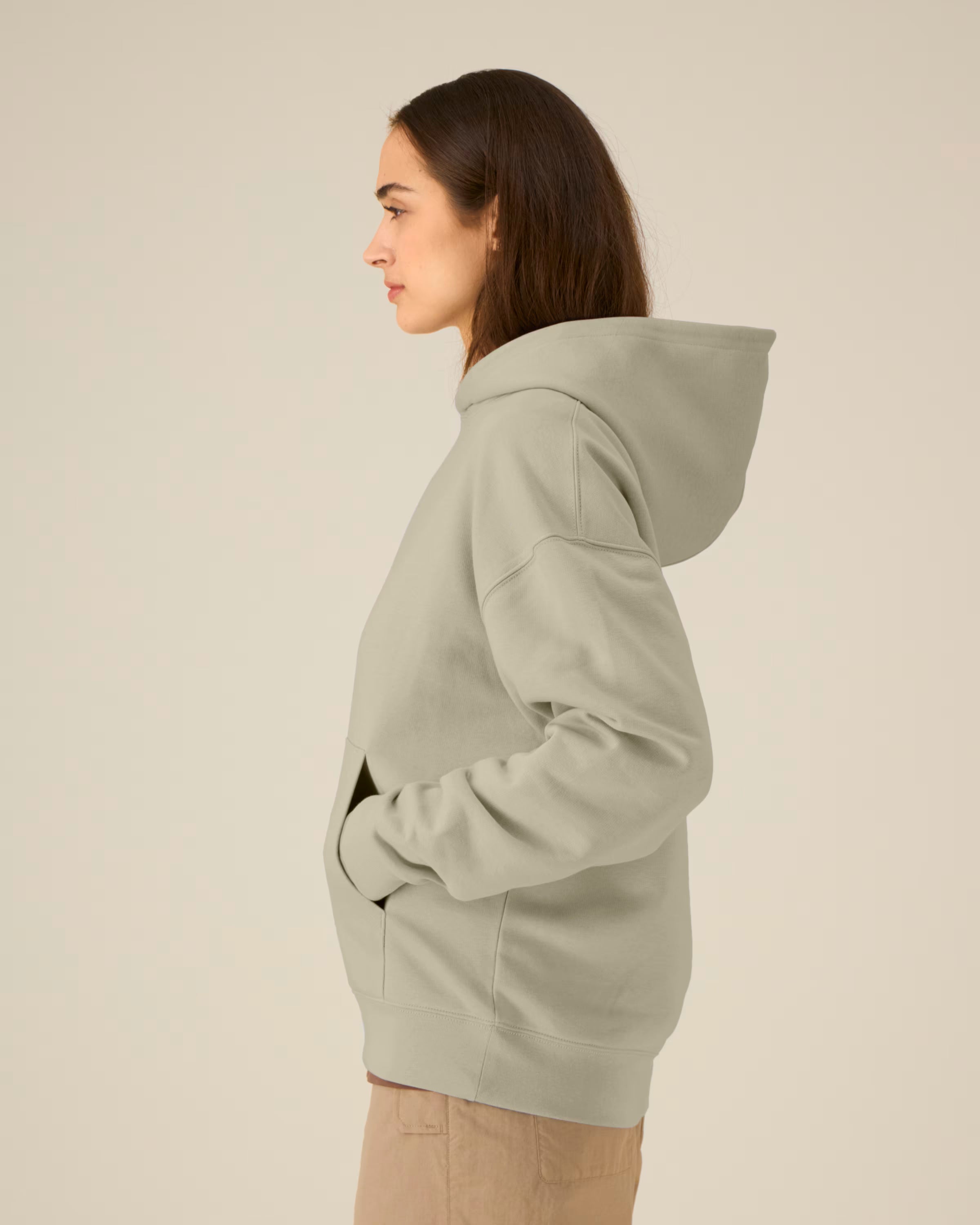 Person wearing a light gray unisex cotton hoodie on a beige background