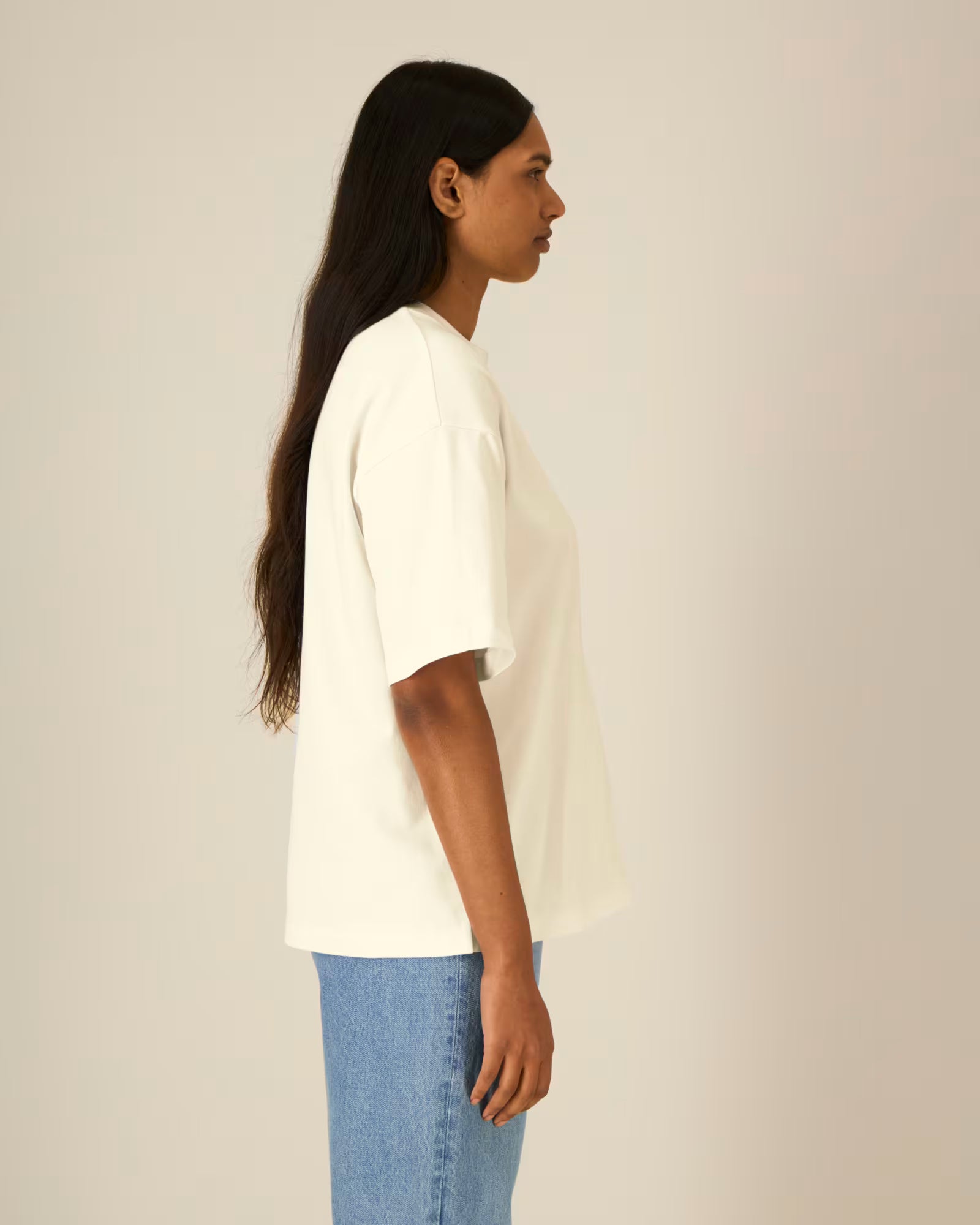 Side view of a female model wearing a natural beige cotton t-shirt in studio