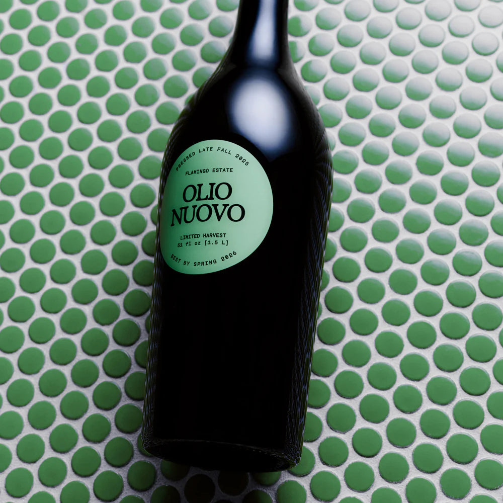 Bottle of Olio Nuovo oil on a green and white patterned surface