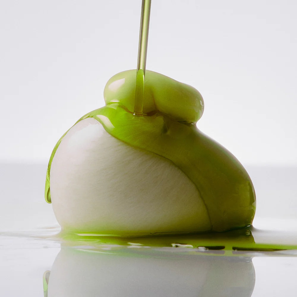 Green and white object with a liquid being poured over it on a reflective surface.