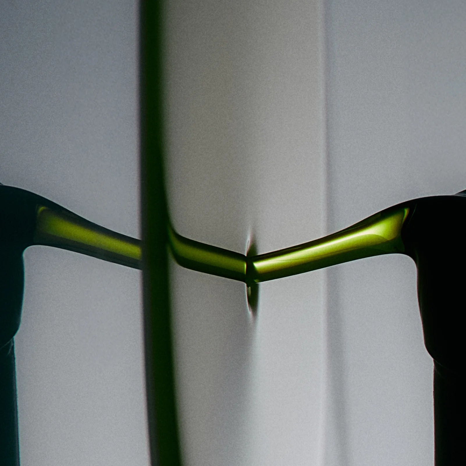 Close-up of a green bicycle handlebar against a gray background